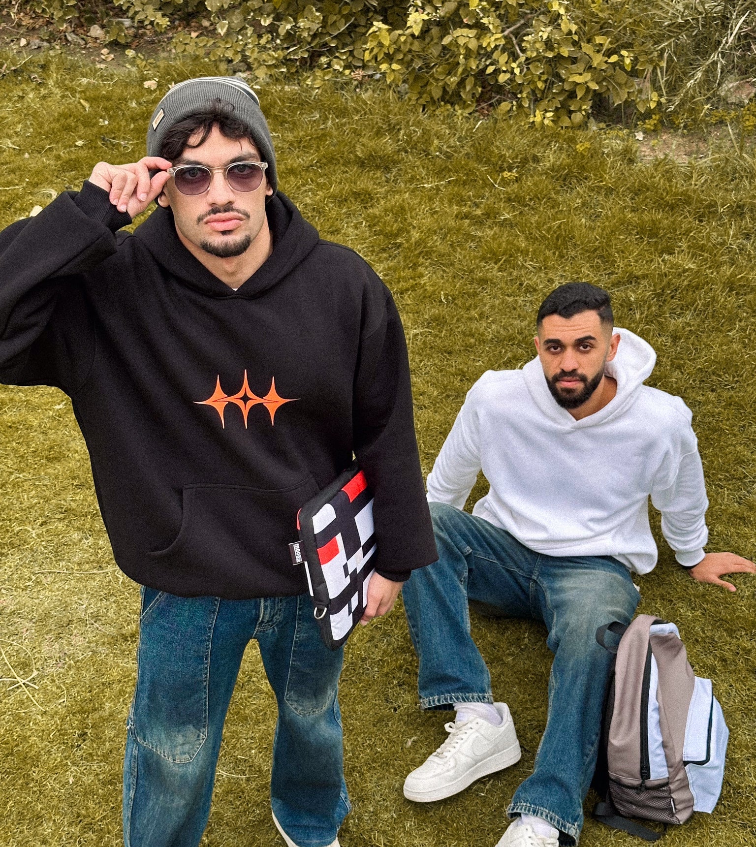 Two people sitting on grass with a forest background